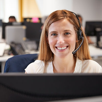 Foveo Client Care Specialist sitting at computer with headset on.